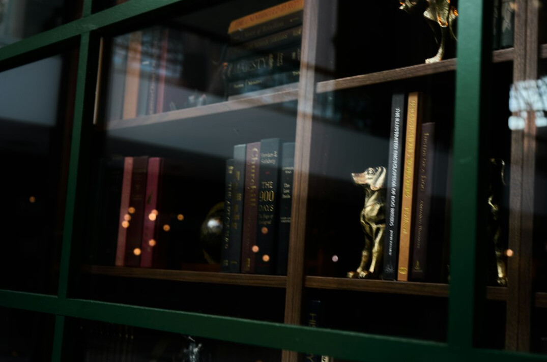 Tall library shelves filled with old books in warm light