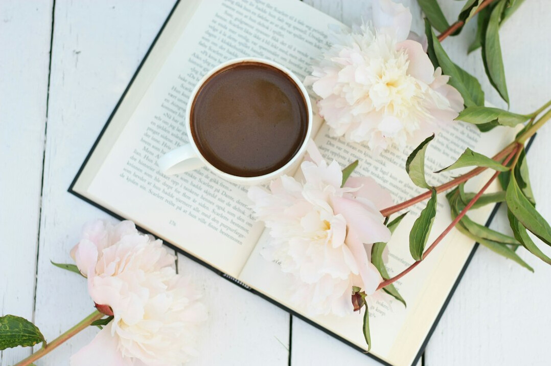 Open book on a table with a cup of coffee