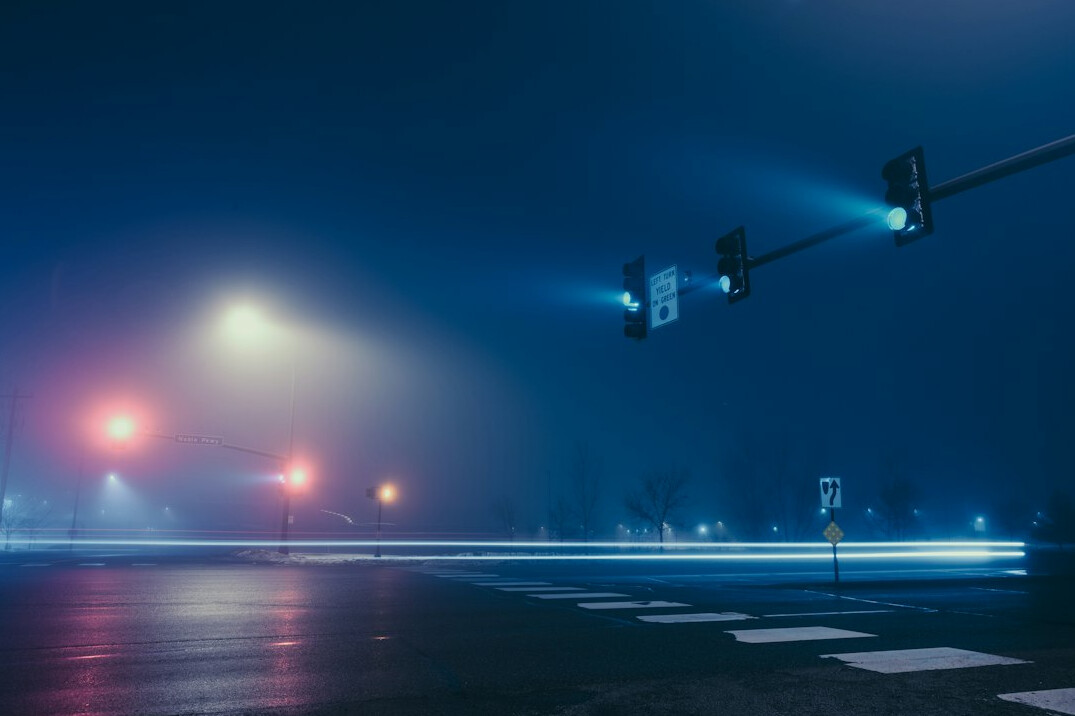 City street at dusk with lights and mist